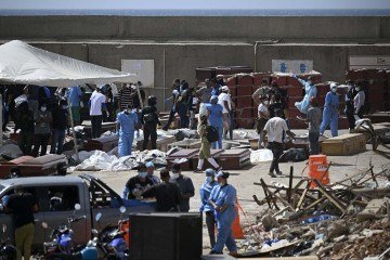 Médicos legistas trabalham entre sacos mortuários dispostos no chão do principal porto do país  -  (crédito: PARRA / AFP)
