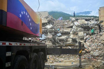 Trabalhadores removem escombros ao lado de um guindaste móvel com a bandeira da Venezuela, no local de um prédio que desabou em Caraballeda, no estado de La Guaira, Venezuela, em 12 de julho de 2026, após dois terremotos que atingiram a região - (crédito: AFP) Trabalhadores removem escombros ao lado de um guindaste móvel com a bandeira da Venezuela, no local de um prédio que desabou em Caraballeda, no estado de La Guaira, Venezuela, em 12 de julho de 2026, após dois terremotos que atingiram a região - (crédito: AFP)