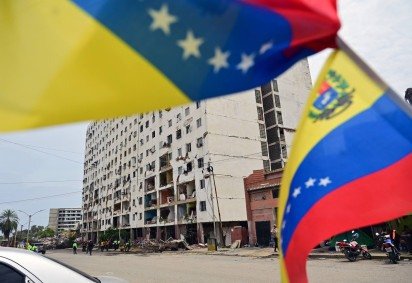  Venezuelan flags flutter in front of a partially collapsed building in Caraballeda, La Guaira state, Venezuela, on July 12, 2026, following twin earthquakes that struck the region. The death toll from the twin earthquakes that struck Venezuela on June 24 has risen to more than 4,300, National Assembly President Jorge Rodriguez said on July 11. (Photo by MARTIN BERNETTI / AFP)
       -  (crédito:  AFP) - Venezuelan flags flutter in front of a partially collapsed building in Caraballeda, La Guaira state, Venezuela, on July 12, 2026, following twin earthquakes that struck the region. The death toll from the twin earthquakes that struck Venezuela on June 24 has risen to more than 4,300, National Assembly President Jorge Rodriguez said on July 11. (Photo by MARTIN BERNETTI / AFP)
       -  (crédito:  AFP)