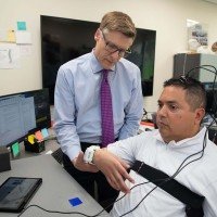  Chad Bouton demonstra a estimulação não invasiva no paciente Keith Thomas: tecnologia devolveu autonomia perdida após um acidente de mergulho -  (crédito: Feinstein Institutes for Medical Research/Divulgação )