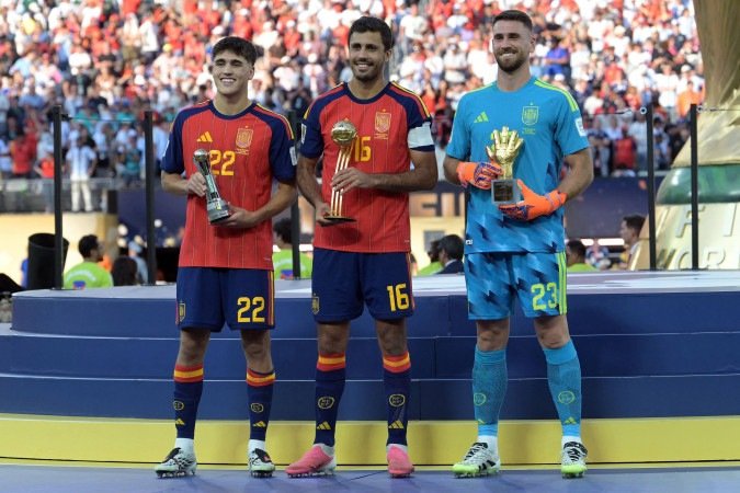 Spain's defender #22 Pau Cubarsi, Spain's midfielder #16 Rodri and Spain's goalkeeper #23 Unai Simon pose on the podium after respectively receiving the Young Player, Golden Ball, Golden Glove awards during the award ceremony of the 2026 World Cup football tournament final match between Spain and Argentina at the New York/New Jersey Stadium in East Rutherford on July 19, 2026. 