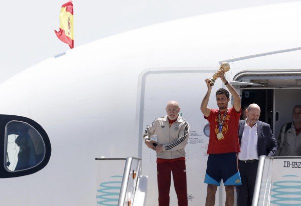 O capitão da Espanha, Rodri, ergue o troféu ao lado do técnico Luis de la Fuente (à esquerda) ao desembarcarem do avião, vindos dos EUA. -  (crédito:  AFP)