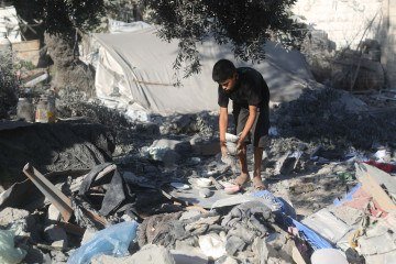 Jovem palestino coleta objetos dos escombros após ataques isrealenses em Gaza -  (crédito:  Eyad Baba / AFP)