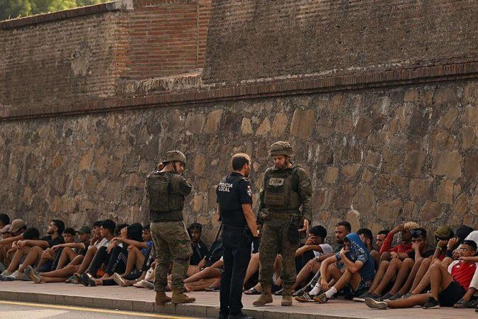 A polícia escoltou migrantes para fora do território espanhol neste sábado - (crédito: Reuters) A polícia escoltou migrantes para fora do território espanhol neste sábado - (crédito: Reuters)