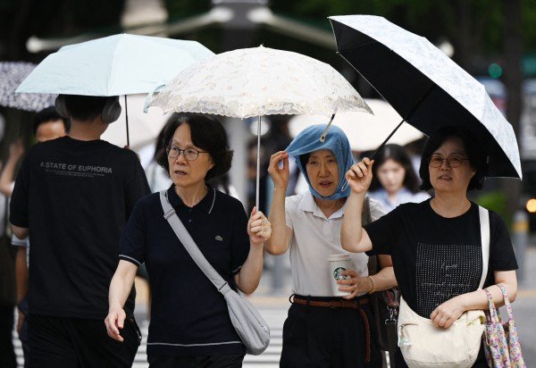 Em Seul, pessoas tentam se proteger das altas temperatura com sombrinhas: alerta é que o calor pode aumentar  -  (crédito:  AFP)