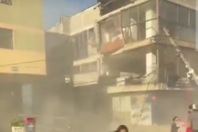 Mulher corre na tentiva de se proteger dos destro&ccedil;os caindo dos pr&eacute;dios, em Cali 