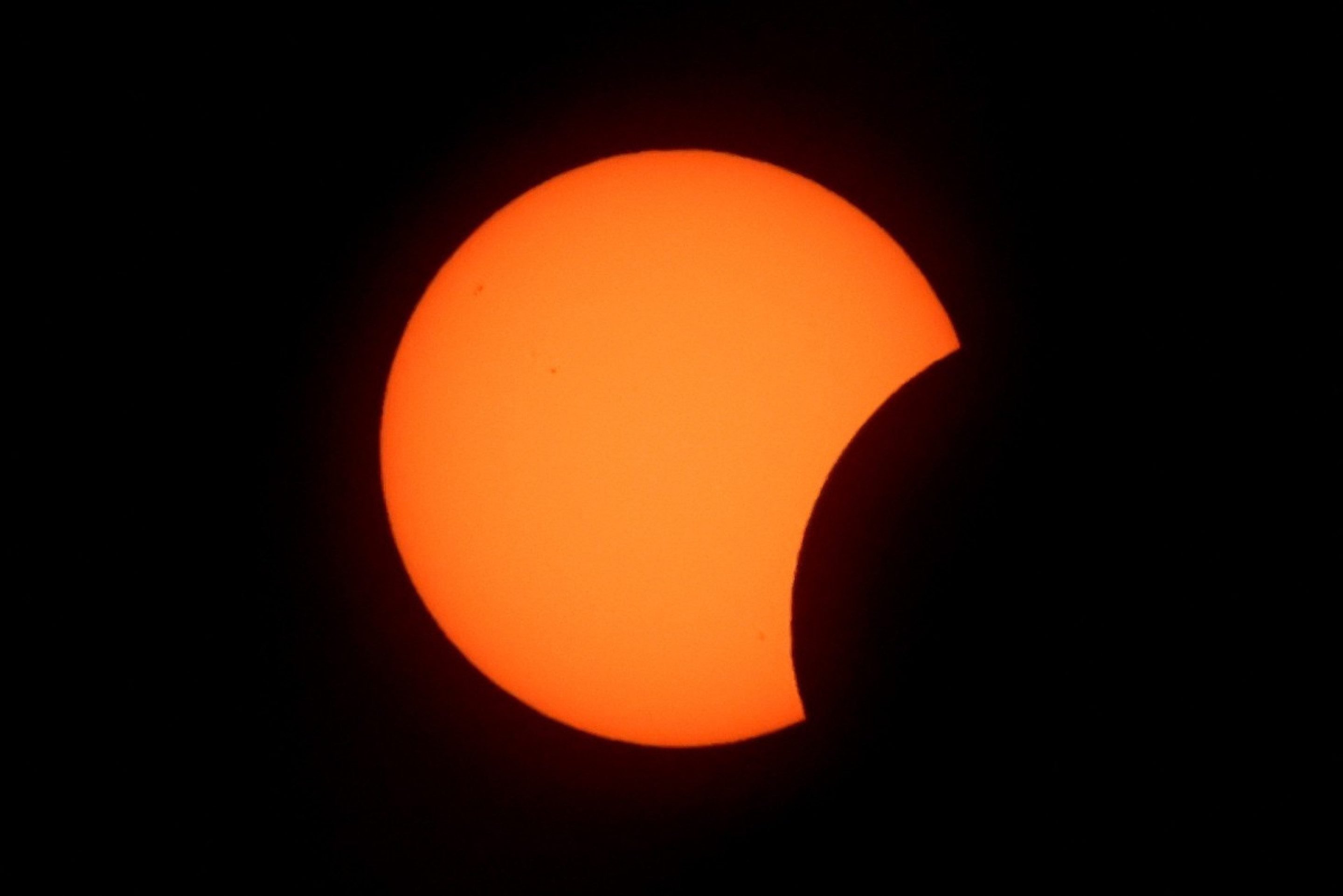 A Lua cobre parcialmente o Sol durante as fases iniciais do eclipse solar total, visto da praia de La Zurriola, em San Sebasti&aacute;n, em 12 de agosto de 2026      