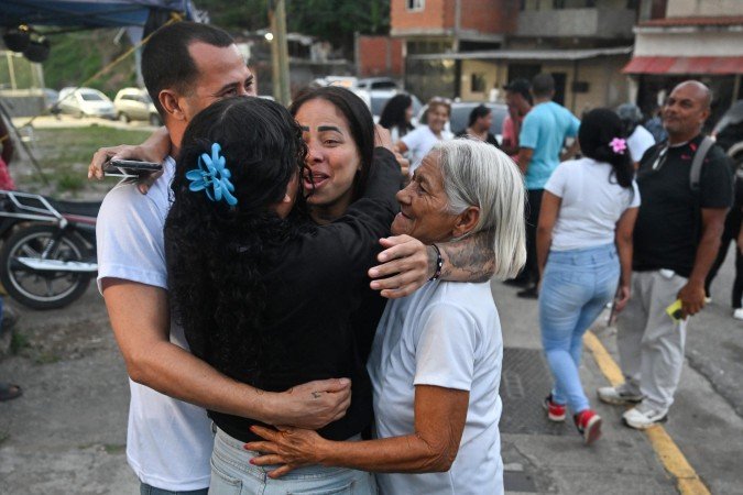 Former political prisoner Angela Vasquez (C) reunites with relatives after her release outside El Rodeo I prison in Guatire, Miranda state, Venezuela, on August 14, 2026. Venezuela released 131 political prisoners on August 14, including a woman accused of involvement in an alleged drone attack against ousted leader Nicolas Maduro, following a pledge made the previous day by the opposition representative in talks with the interim government to help secure their release. (Photo by Juan BARRETO / AFP)
- (crédito: Juan Barreto/AFP) Former political prisoner Angela Vasquez (C) reunites with relatives after her release outside El Rodeo I prison in Guatire, Miranda state, Venezuela, on August 14, 2026. Venezuela released 131 political prisoners on August 14, including a woman accused of involvement in an alleged drone attack against ousted leader Nicolas Maduro, following a pledge made the previous day by the opposition representative in talks with the interim government to help secure their release. (Photo by Juan BARRETO / AFP)
- (crédito: Juan Barreto/AFP)