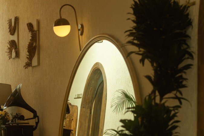 O espelho oval entra na composição não apenas para decorar, mas para integrar o espaço, refletindo a autenticidade e o aconchego do lar
