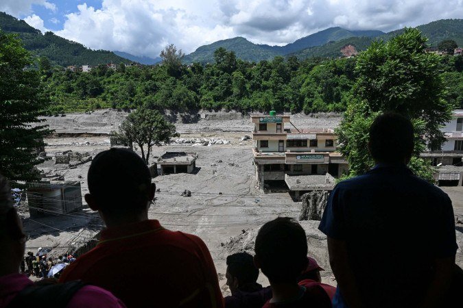 Abrigados sobre telhado, moradores observam destruição em Trishuli