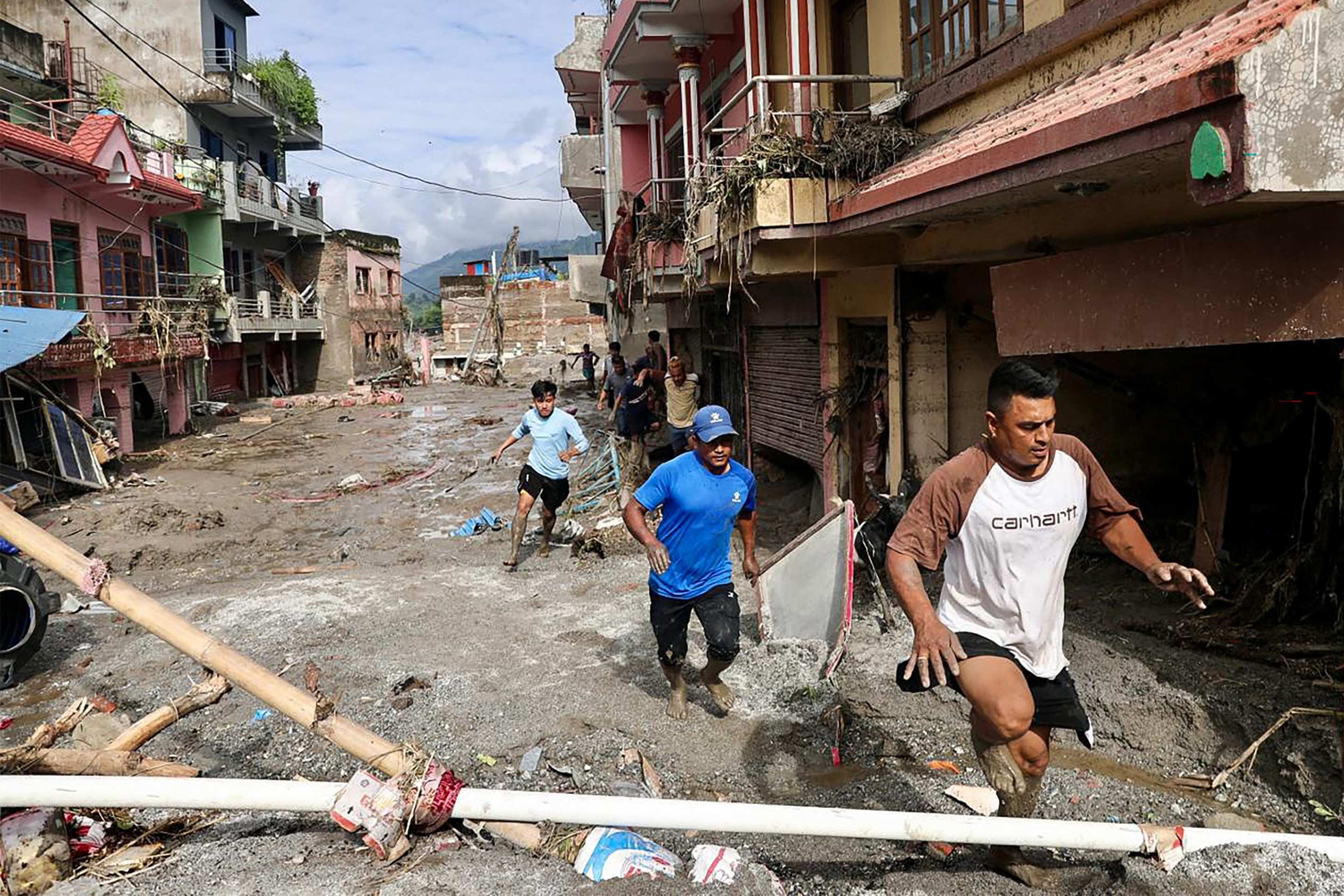 Residentes de Devighat, na municipalidade de Bidur, caminham por rua atingida pela avalanche de lama 
