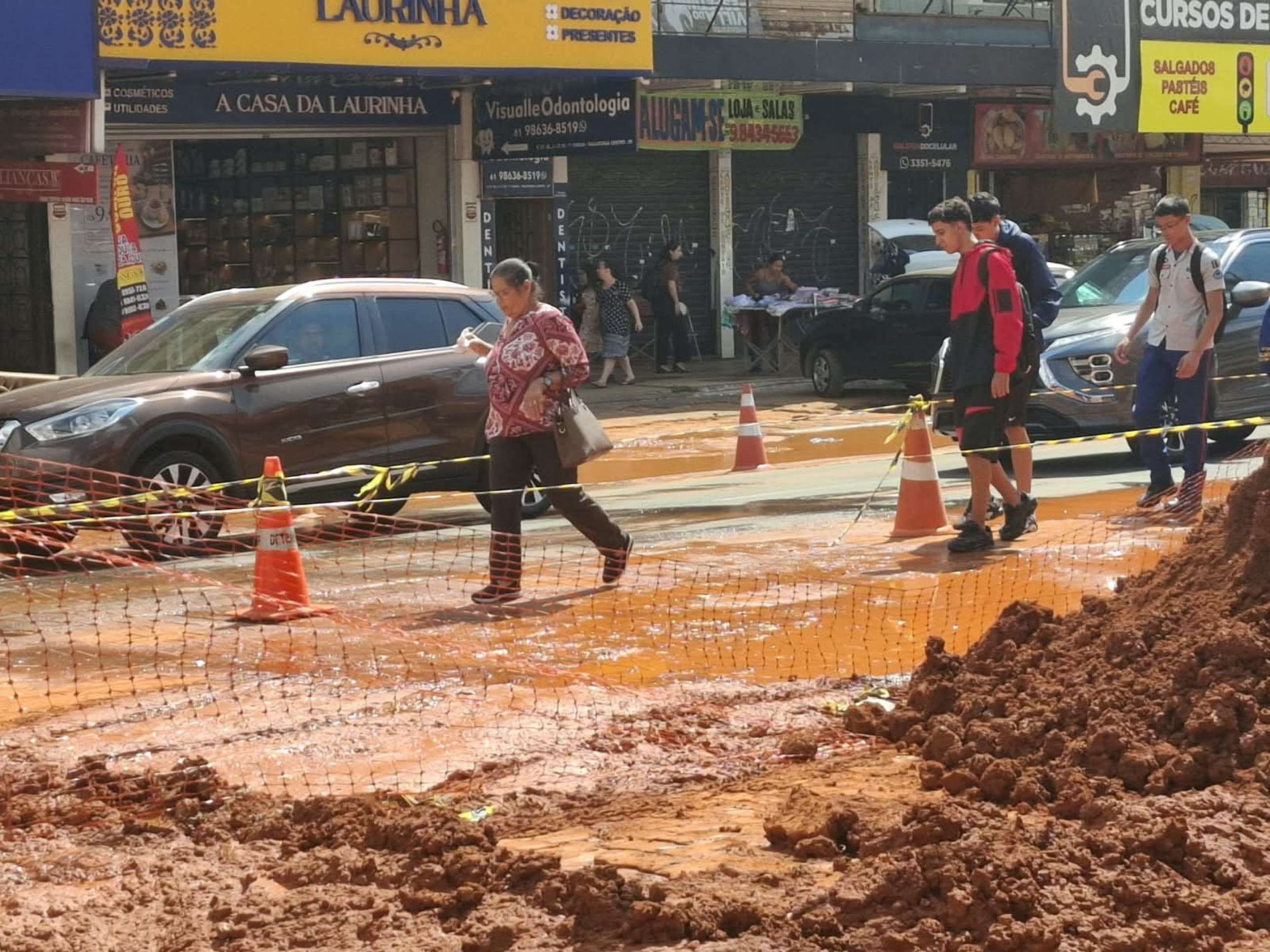 Pedestres contornam &aacute;rea isolada para passar para o outro lado da cal&ccedil;ada