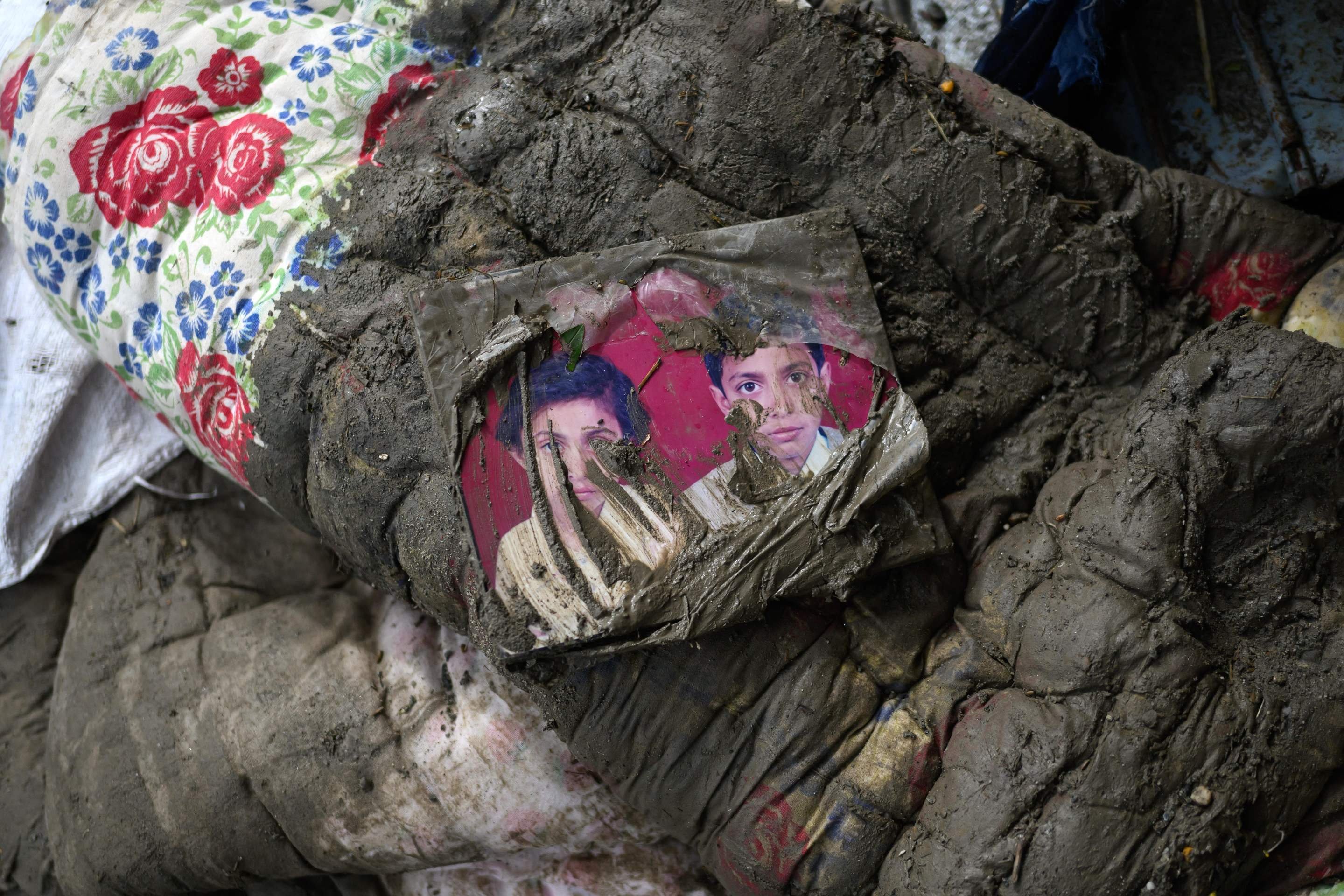 Fotografia de fam&iacute;lia colocada sobre colch&atilde;o coberto de lama, do lado de fora de uma casa em Devighat, no distrito de Nuwakot