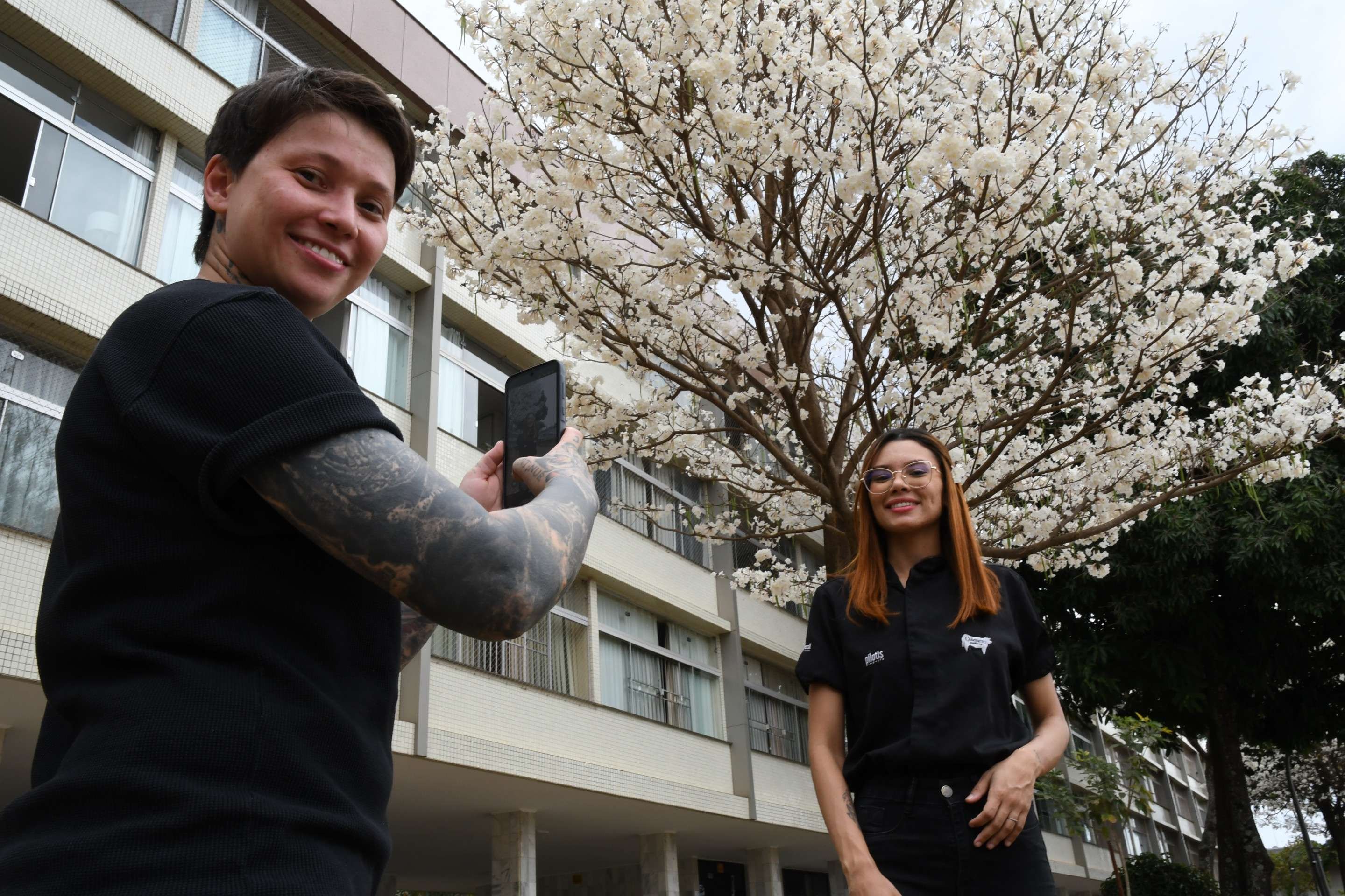Daiane Caroline Gomes tira foto de Laune Souza, em frente &agrave; &aacute;rvore