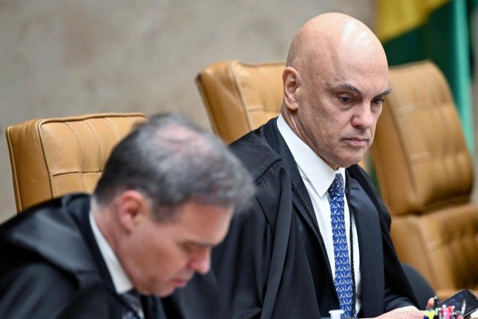 Brazilian Supreme Court Justice Alexandre de Moraes (R) looks on next to Justice Andre Mendonca during a court session at the Supreme Federal Court (STF) in Brasilia on September 2, 2026. The president of Brazil's Supreme Court on September 2 urged citizens to maintain trust in the institution as it battles a scandal involving a polarizing judge who has crossed swords with the right and Elon Musk. Justice Alexandre de Moraes, famous for overseeing the coup trial of far-right ex-president Jair Bolsonaro and for battling disinformation on Musk's X platform, has come under intense scrutiny over text messages he received from a fraud-accused banker. (Photo by Evaristo Sa / AFP)
Caption - (crédito: AFP) Brazilian Supreme Court Justice Alexandre de Moraes (R) looks on next to Justice Andre Mendonca during a court session at the Supreme Federal Court (STF) in Brasilia on September 2, 2026. The president of Brazil's Supreme Court on September 2 urged citizens to maintain trust in the institution as it battles a scandal involving a polarizing judge who has crossed swords with the right and Elon Musk. Justice Alexandre de Moraes, famous for overseeing the coup trial of far-right ex-president Jair Bolsonaro and for battling disinformation on Musk's X platform, has come under intense scrutiny over text messages he received from a fraud-accused banker. (Photo by Evaristo Sa / AFP)
Caption - (crédito: AFP)