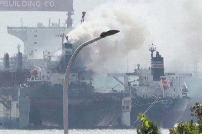 Esta captura de tela de um vídeo feito em 10 de setembro de 2026 e fornecido pela Qingdao WoLin Packaging mostra fumaça saindo de um navio de carga em um porto de Qingdao, no leste da China. - (crédito: AFP) Esta captura de tela de um vídeo feito em 10 de setembro de 2026 e fornecido pela Qingdao WoLin Packaging mostra fumaça saindo de um navio de carga em um porto de Qingdao, no leste da China. - (crédito: AFP)