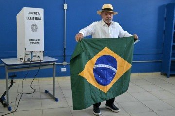 O presidente do Brasil e candidato à reeleição pelo Partido dos Trabalhadores (PT), de esquerda, Luiz Inácio Lula da Silva, segura uma bandeira do Brasil ao votar durante a eleição presidencial em uma seção eleitoral em São Bernardo do Campo, estado de São Paulo, Brasil, em 4 de outubro de 2026 - (crédito: NELSON ALMEIDA / AFP) O presidente do Brasil e candidato à reeleição pelo Partido dos Trabalhadores (PT), de esquerda, Luiz Inácio Lula da Silva, segura uma bandeira do Brasil ao votar durante a eleição presidencial em uma seção eleitoral em São Bernardo do Campo, estado de São Paulo, Brasil, em 4 de outubro de 2026 - (crédito: NELSON ALMEIDA / AFP)