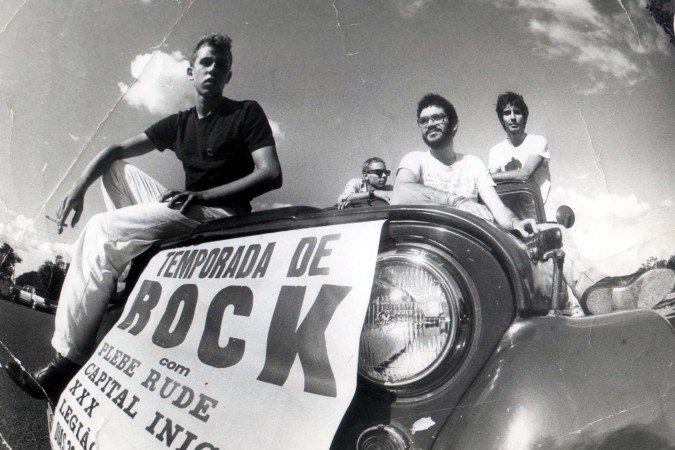 Da esquerda para a direita: os músicos André Muller, Gutje , Renato Russo e Flávio Lemos, com o cartaz  da Temporada de Rock com Plebe Rude, Capital Inicial, XXX, Legião Urbana e Dias 22, em abril de 1983     