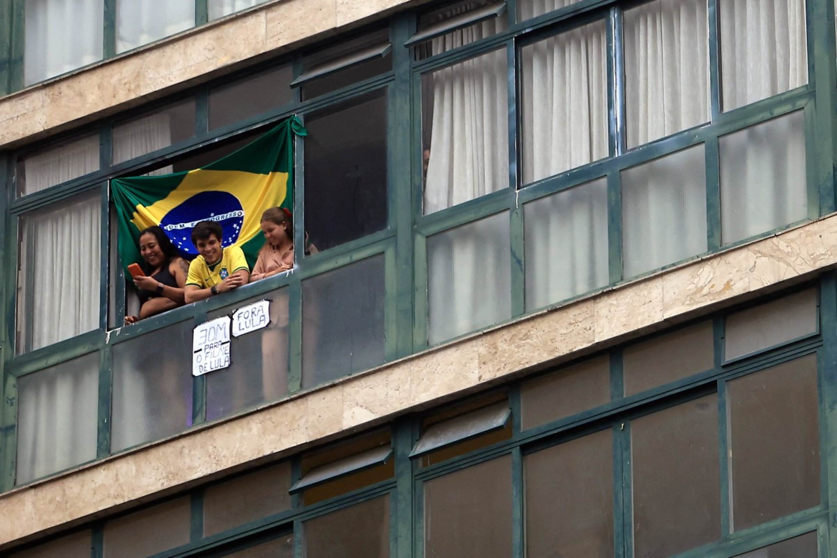  People watch from a window displaying signs reading 