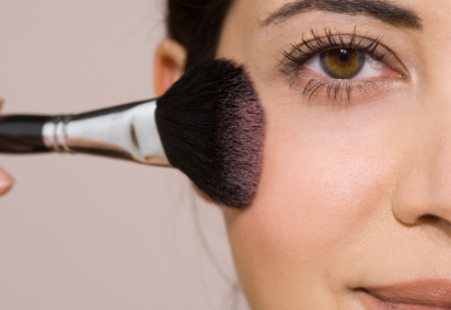 Mulher de cabelos castanhos passa blush nas bochechas com pincel de maquiagem -  (crédito: Canva Pro) -Mulher de cabelos castanhos passa blush nas bochechas com pincel de maquiagem -  (crédito: Canva Pro)