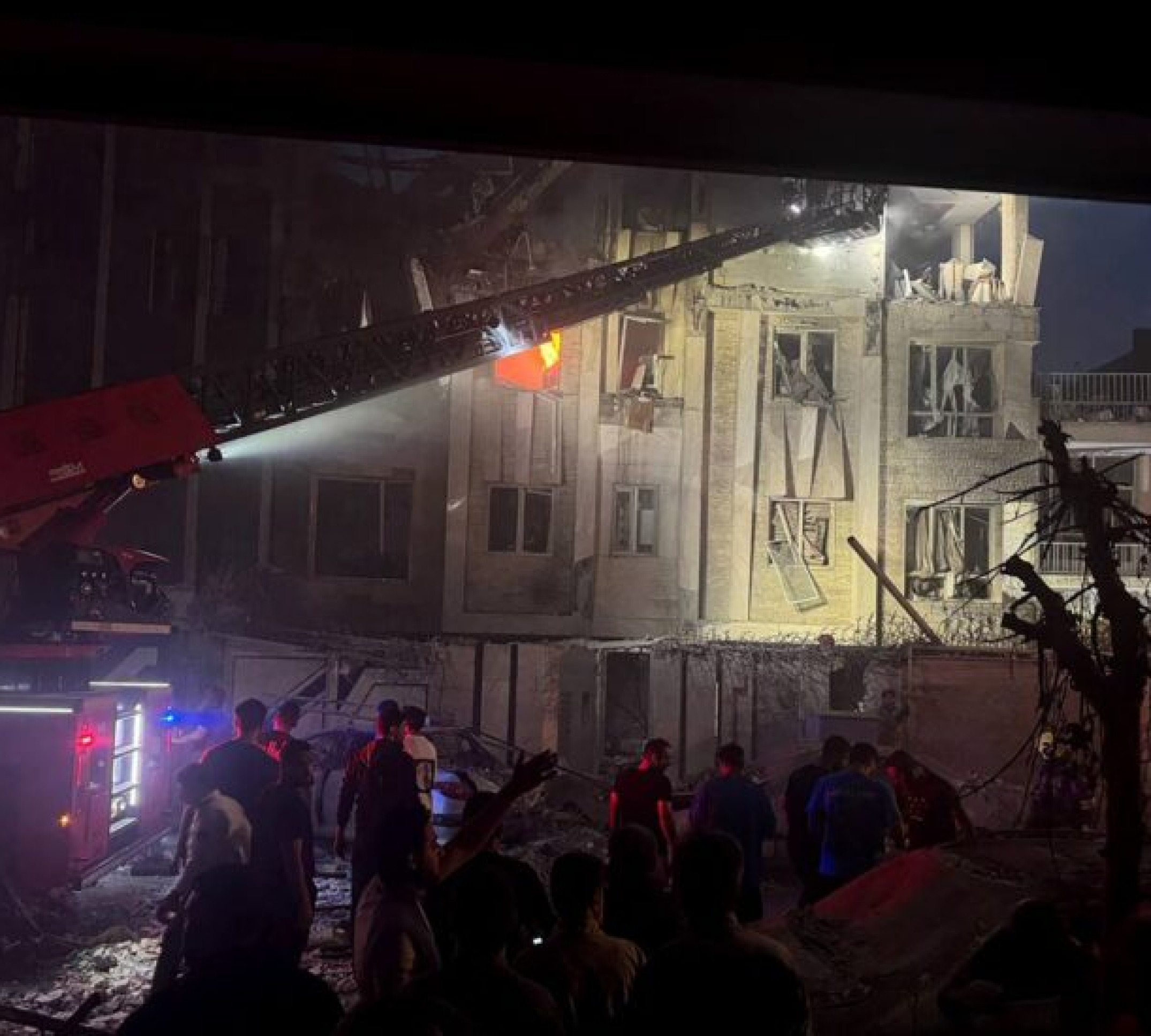 Espectadores e equipes de resgate em frente a um prédio vitimado pelo fogo depois de um ataque israelense, nesta sexta-feira (13/6), em Teerã, capital do Irã